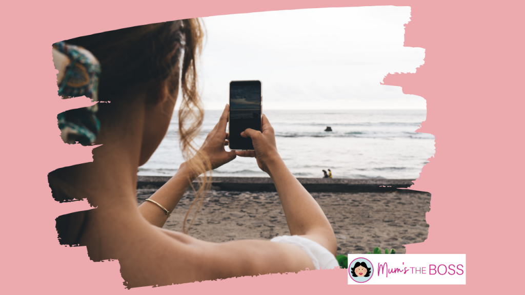 Image shot from behind of a woman taking a photo of a beach
